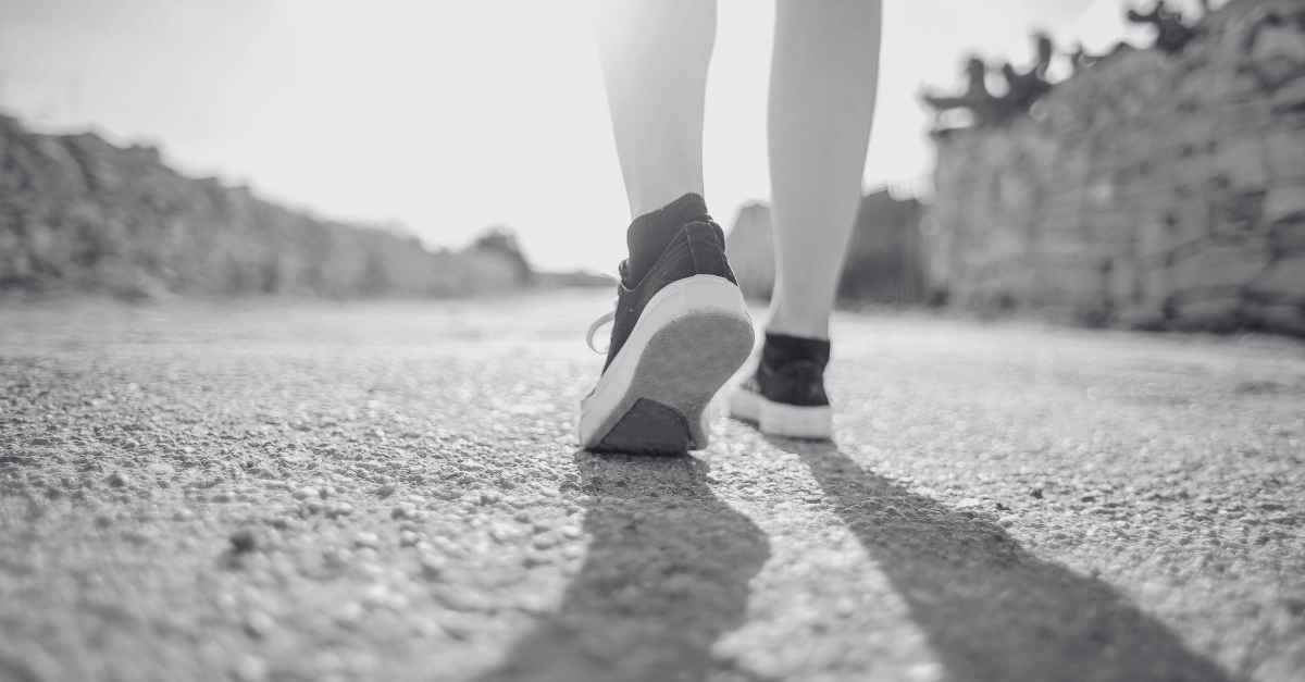 A midlife woman walking briskly outdoors, looking relaxed and energized